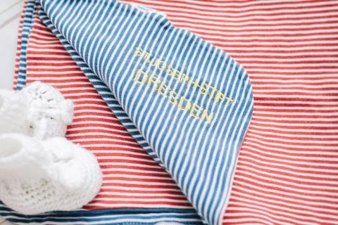 geburtshilfe, Detail: Babyschuhe in weiß und Babydecke mit SJS-Monogramm
